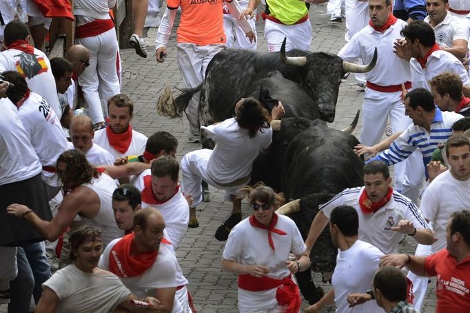 A runner, identified by a Navarran government spokesperson as a 21-year-old Japanese man from Ikeda, is lifted by his scarf onto the horns of a Dolores Aguirre fighting bull on the the first day of the running of the bulls in Pamplona July 7 2012. The man was dragged for approximately 50 metres (164 feet) and suffered light back injuries. REUTERS/Vincent West (SPAIN - Tags: ANIMALS SOCIETY) Published: Čec. 7, 2012, 9:53 dop.