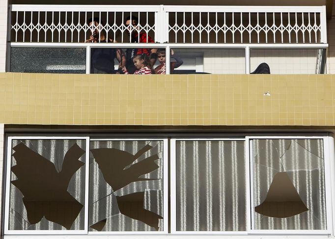 Israelis look out from a building which was damaged after a rocket fired from Gaza landed in the southern city of Ashdod November 16, 2012. Israel has started drafting 16,000 reserve troops, the military said on Friday, in a sign that violence could escalate further with Palestinian militants in the Gaza Strip. REUTERS/Amir Cohen (ISRAEL - Tags: POLITICS CIVIL UNREST MILITARY) Published: Lis. 16, 2012, 7:49 dop.