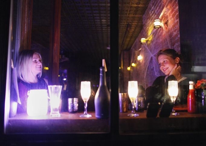 Women sit in a bar lit by candlelight in the Lower East Village in the aftermath of Hurricane Sandy in New York October 31, 2012. New York City and the sodden U.S. Northeast began an arduous journey back to normal on Wednesday after mammoth storm Sandy killed at least 64 people in a rampage that swamped coastal cities and cut power to millions. REUTERS/Carlo Allegri (UNITED STATES - Tags: SOCIETY ENVIRONMENT DISASTER FOOD) Published: Lis. 1, 2012, 3:42 dop.