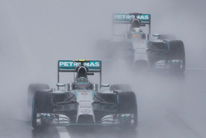 Mercedes Formula One driver Nico Rosberg of Germany leads team mate Lewis Hamilton of Britain behind a safety car (unseen) as they start the first lap of the rain-affecte