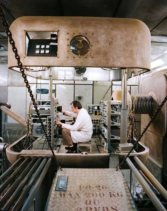 Technik v CERN upravuje elektroniku iontového zdroje na vysokonapěťové platformě, 1974. Foto zachycuje detaily údržby urychlovačů. Kolorovaný snímek