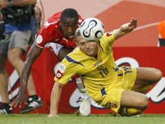 Švýcar Johan Djourou a Andrij Voronin z Ukrajiny (ve žlutém) bojují na zemi o míč.