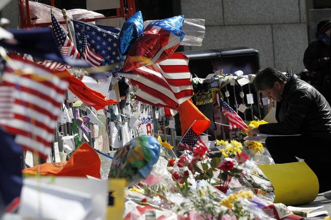 A man kneels down to place a message on a makeshift memorial after observing a moment of silence for the victims of the Boston Marathon bombings marking a week to the day of the bombings at a memorial on Boylston Street in Boston, Massachusetts April 22, 2013. REUTERS/Jessica Rinaldi (UNITED STATES - Tags: CRIME LAW CIVIL UNREST) Published: Dub. 22, 2013, 8:01 odp.