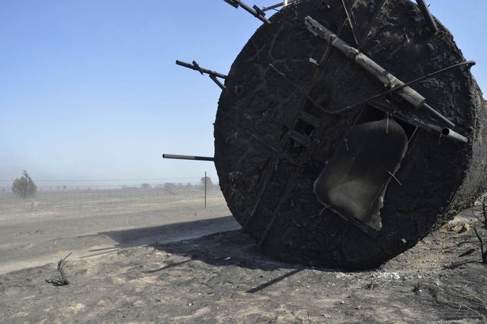 A tank lies on its side, burnt by the so-called Dump Fire, just outside an explosives plant near Saratoga Springs, Utah, June 23, 2012. A raging Utah brush fire ignited by target shooting in dry grass has forced some 8,000 people from their homes in two small communities since June 22 as high winds fanned flames toward a nearby explosives factory, authorities said. REUTERS/Jeff McGrath (UNITED STATES - Tags: ENVIRONMENT DISASTER) Published: Čer. 24, 2012, 1:56 dop.