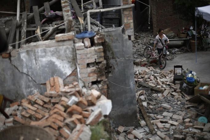 A woman pushes her bicycle past debris after Saturday's earthquake in Lushan county, April 22, 2013. Rescuers struggled to reach a remote, rural corner of southwestern China on Sunday as the toll of the dead and missing from the country's worst earthquake in three years climbed to 208 with almost 1,000 serious injuries. The 6.6 magnitude quake struck in Lushan county, near the city of Ya'an in the southwestern province of Sichuan, close to where a devastating 7.9 quake hit in May 2008, killing 70,000. REUTERS/Aly Song (CHINA - Tags: DISASTER SOCIETY) Published: Dub. 22, 2013, 3:51 dop.