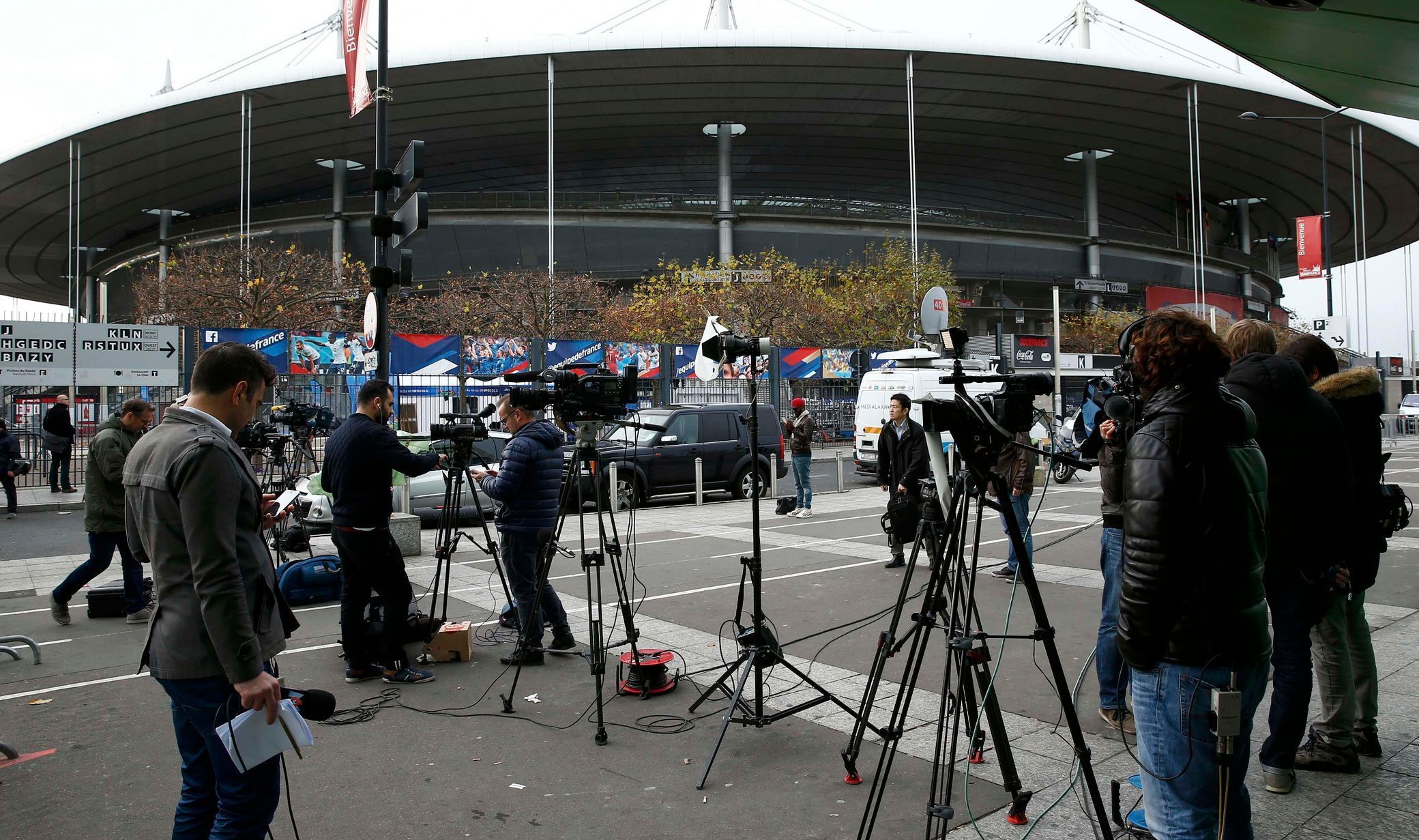 Media stand behind a barrier in front of the Stade de France stadium the morning after a series of deadly attacks in Paris