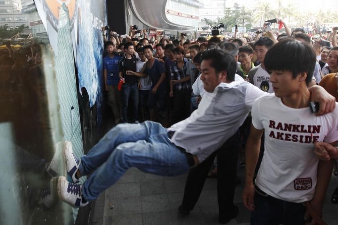 demonstrator kicks a glass window of the Japanese Seibu department store during a protest against Japan's decision to purchase disputed islands, which Japan calls the Senkaku and China calls the Diaoyu, in Shenzhen, south China's Guangdong province September 16, 2012. Torrid protests against Japan flared in Chinese cities for a second day on Sunday, with the government struggling to find a balance between venting public anger and containing violence that could backfire ahead of a delicate leadership succession. REUTERS/Tyrone Siu (CHINA - Tags: POLITICS CIVIL UNREST BUSINESS)