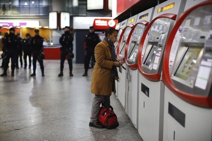 A passenger purchases a ticket near a line of police at Atocha rail station during a 24-hour nationwide general strike in Madrid, November 14, 2012. Spanish and Portuguese workers staged the first coordinated strike across the Iberian peninsula on Wednesday, shutting down transport, grounding flights and closing schools to protest austerity measures and tax hikes. REUTERS/Paul Hanna (SPAIN - Tags: POLITICS CIVIL UNREST BUSINESS EMPLOYMENT TRANSPORT) Published: Lis. 14, 2012, 9:12 dop.