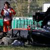Course officials stand next to the car of McLaren Formula One driver Kevin Magnussen of Denmark after he crashed during the second practice session of the Australian F1 Grand Prix at the Albert Park c