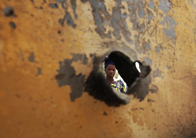 A woman is seen through a bullet hole of a vehicle, believed to belong to Islamist rebels and destroyed during French air strikes, in the recently liberated town of Diabaly January 24, 2013. REUTERS/Eric Gaillard (MALI - Tags: CIVIL UNREST CONFLICT MILITARY POLITICS) Published: Led. 24, 2013, 5:42 odp.