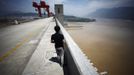 A man stands on the Three Gorges dam in Yichang, Hubei province in this August 9, 2012 file photo. China relocated 1.3 million people during the 17 years it took to complete the Three Gorges dam. Even after finishing the $59 billion project last month, the threat of landslides along the dam's banks will force tens of thousands to move again. It's a reminder of the social and environmental challenges that have dogged the world's largest hydroelectric project. While there has been little protest among residents who will be relocated a second time, the environmental fallout over other big investments in China has become a hot-button issue ahead of a leadership transition this year. Picture taken on August 9, 2012. To match story CHINA-THREEGORGES/ REUTERS/Carlos Barria/Files (CHINA - Tags: POLITICS ENVIRONMENT BUSINESS ENERGY) Published: Srp. 22, 2012, 8:40 odp.