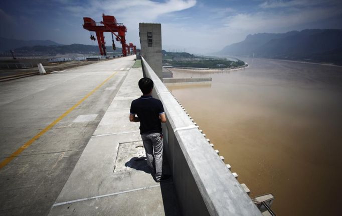 A man stands on the Three Gorges dam in Yichang, Hubei province in this August 9, 2012 file photo. China relocated 1.3 million people during the 17 years it took to complete the Three Gorges dam. Even after finishing the $59 billion project last month, the threat of landslides along the dam's banks will force tens of thousands to move again. It's a reminder of the social and environmental challenges that have dogged the world's largest hydroelectric project. While there has been little protest among residents who will be relocated a second time, the environmental fallout over other big investments in China has become a hot-button issue ahead of a leadership transition this year. Picture taken on August 9, 2012. To match story CHINA-THREEGORGES/ REUTERS/Carlos Barria/Files (CHINA - Tags: POLITICS ENVIRONMENT BUSINESS ENERGY) Published: Srp. 22, 2012, 8:40 odp.