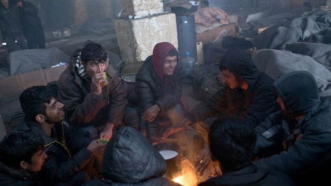 Uprchlíci z Afghánistánu se zahřívají u ohně v opuštěném skladišti poblíž hlavního nádraží v Bělehradě.