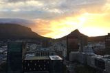 A pokud potom na jednu z výškových budov vystoupáte, může se vám naskytnout pohled na takovýto západ slunce. Vpravo Lions Head, vlevo Table mountain.
