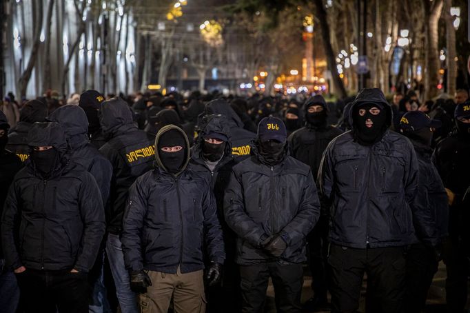 Maskovaní muži, kteří útočí na demonstranty.