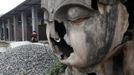 A survivor smokes near a damaged Buddha statue two days after an earthquake hit Lushan county of Ya'an, Sichuan province April 22, 2013. Rescuers struggled to reach a remote, rural corner of southwestern China on Sunday as the toll of the dead and missing from the country's worst earthquake in three years climbed to 208 with almost 1,000 serious injuries. The 6.6 magnitude quake struck in Lushan county, near the city of Ya'an in the southwestern province of Sichuan, close to where a devastating 7.9 quake hit in May 2008, killing 70,000. REUTERS/Jason Lee (CHINA - Tags: DISASTER RELIGION) Published: Dub. 22, 2013, 9:19 dop.