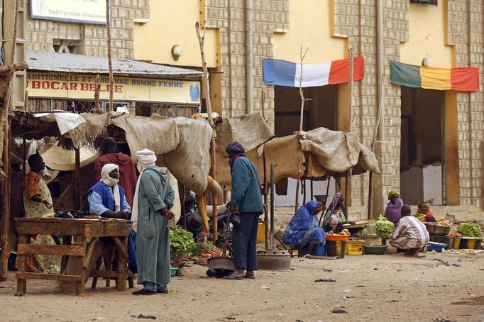 Men sit outside a shop as Malian and French flags decorate a street in Timbuktu January 31, 2013. Mali's president offered Tuareg rebels talks on Thursday in a bid for national reconciliation after a French-led offensive drove their Islamist former allies into mountain hideaways. REUTERS/Benoit Tessier (MALI - Tags: POLITICS CIVIL UNREST CONFLICT SOCIETY) Published: Led. 31, 2013, 6:34 odp.