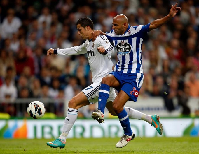 Portugalský fotbalista Cristiano Ronaldo z Realu Madrid uniká před Manuelem Pablem v utkání La Ligy 2012/13 s Deportivem La Coruňa.