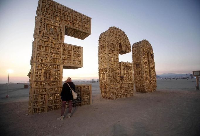 Ruth Kidd explores the art piece "Ego" before sunrise during the Burning Man 2012 "Fertility 2.0" arts and music festival in the Black Rock Desert of Nevada, August 29, 2012. More than 60,000 people from all over the world have gathered at the sold out festival, which is celebrating its 26th year, to spend a week in the remote desert cut off from much of the outside world to experience art, music and the unique community that develops.