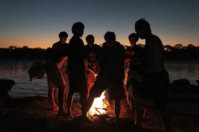 Yawalapiti men warm themselves over a fire after bathing in the Tuatuari River during this year's 'quarup,' a ritual held over several days to honour in death a person of great importance to them, in the Xingu National Park, Mato Grosso State, August 18, 2012. This year the Yawalapiti tribe honoured two people - a Yawalapiti Indian who they consider a great leader, and Darcy Ribeiro, a well-known author, anthropologist and politician known for focusing on the relationship between native peoples and education in Brazil. Picture taken August 18, 2012. REUTERS/Ueslei Marcelino (BRAZIL - Tags: SOCIETY ENVIRONMENT) FOR EDITORIAL USE ONLY. NOT FOR SALE FOR MARKETING OR ADVERTISING CAMPAIGNS. ATTENTION EDITORS - PICTURE 27 OF 37 FOR THE PACKAGE 'THE YAWALAPITI QUARUP RITUAL' Published: Srp. 29, 2012, 10:21 dop.