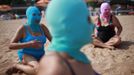 Women, wearing nylon masks, rest on the shore during their visit to a beach in Qingdao, Shandong province July 6, 2012. The mask, which was invented by a woman about seven years ago, is used to block the sun's rays. The mask is under mass production and is on sale at local swimwear stores. REUTERS/Aly Song (CHINA - Tags: SOCIETY TPX IMAGES OF THE DAY ENVIRONMENT TRAVEL) Published: Čec. 6, 2012, 4:03 odp.