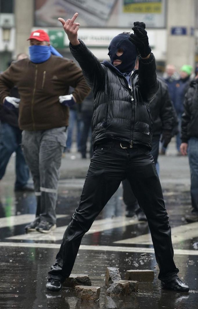 An Arcelor Mittal worker from Liege gestures in front of riot police during a demonstration outside Prime Minister Elio Di Rupo's office in Brussels January 25, 2013. ArcelorMittal, the world's largest steel producer, plans to shut a coke plant and six finishing lines at its site in Liege, affecting 1,300 employees, the group said on Thursday. REUTERS/Eric Vidal (BELGIUM - Tags: BUSINESS CIVIL UNREST EMPLOYMENT) TEMPLATE OUT Published: Led. 25, 2013, 2:16 odp.