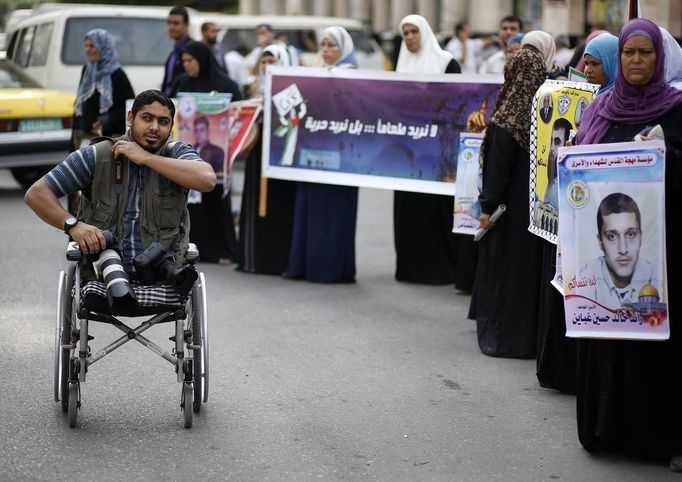 Wheelchair-bound Palestinian freelance photographer Moamen Qreiqea adjusts his camera strap while covering protesters calling for the release of Palestinian prisoners from Israeli jails, in Gaza City October 1, 2012. Qreiqea, 25, lost both his legs in an Israeli air strike in 2008 while taking pictures east of Gaza. The father of two is determined to continue his career despite his disability. REUTERS/Suhaib Salem (GAZA - Tags: MEDIA SOCIETY) Published: Říj. 1, 2012, 3:39 odp.