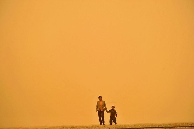 A Chinese woman and her child walk along a street during a sandstorm in Lanzhou, north China's Gansu province on April 23, 2009. Air pollution in China's cities remains very serious, state media quoted a minister as saying, amid an ongoing battle to clean up the skies in the world's largest coal-consuming nation. AFP PHOTO