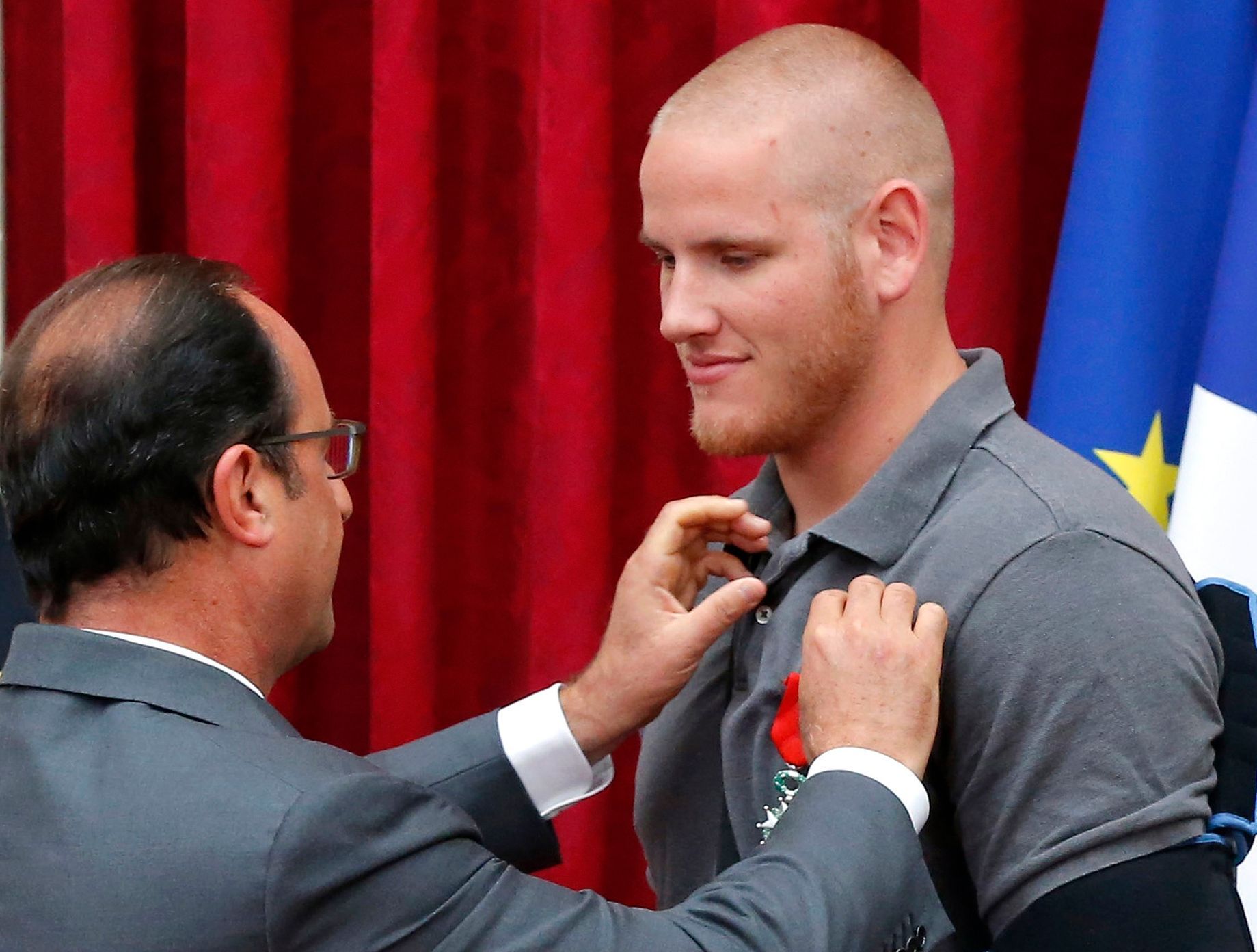 French President Francois Hollande awards US Airman First Class Spencer Stone with the Legion d'Honneur medal as US National Guardsman Alek Skarlatos applauds during a ceremony at the Elysee Palace in
