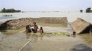 Flood-affected residents move to safer places on a temporary raft next to their submerged huts after heavy rains at Khalabhyan village in the northeastern Indian state of Assam June 30, 2012. Incessant heavy rains in northeast India have caused massive flooding and landslides, killing at least a dozen of people, local media reported. REUTERS/Utpal Baruah (INDIA - Tags: DISASTER ENVIRONMENT) Published: Čer. 30, 2012, 2:39 odp.