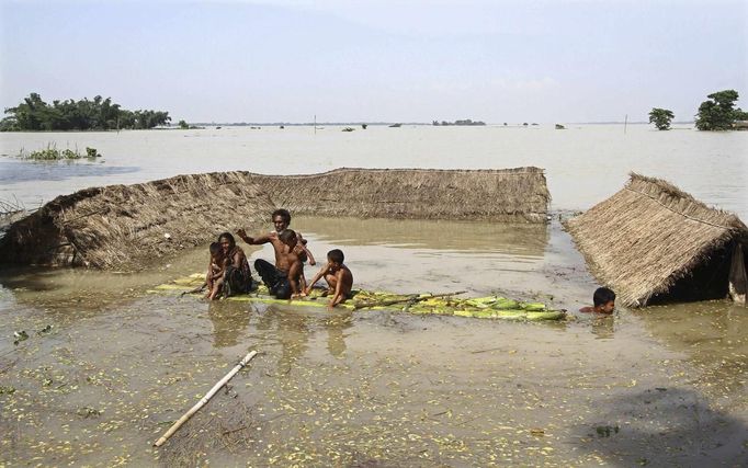 Flood-affected residents move to safer places on a temporary raft next to their submerged huts after heavy rains at Khalabhyan village in the northeastern Indian state of Assam June 30, 2012. Incessant heavy rains in northeast India have caused massive flooding and landslides, killing at least a dozen of people, local media reported. REUTERS/Utpal Baruah (INDIA - Tags: DISASTER ENVIRONMENT) Published: Čer. 30, 2012, 2:39 odp.