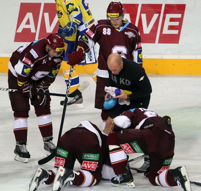 Hokejisté Sparty Praha Jaroslav Hlinka (vlevo) a Michal Broš se sklánějí nad zraněným Petrem Tonem v utkání 8. kola Tipsport extraligy 2012/13 se Zlínem.