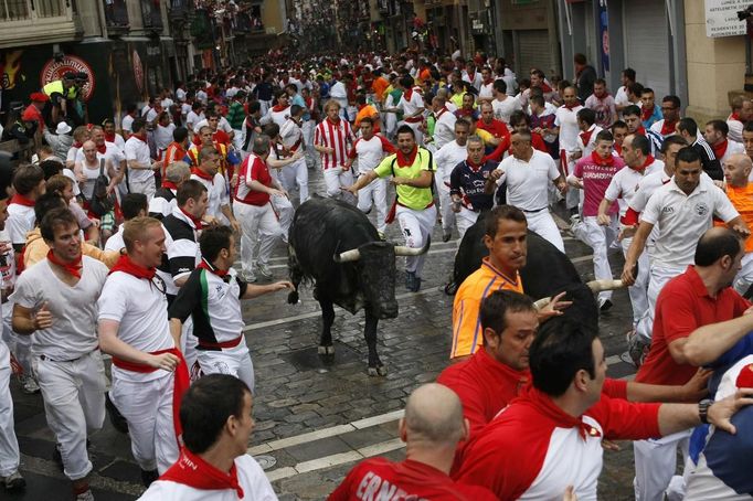 Runners sprint alongside a Dolores Aguirre fighting bull at the Telefonica corner during the first running of the bulls of the San Fermin festival in Pamplona July 7, 2012. One person was gored and four others injured in a run that lasted two minutes and fifty-two seconds, according to local media. REUTERS/Joseba Etxaburu (SPAIN - Tags: SOCIETY ANIMALS) Published: Čec. 7, 2012, 9:13 dop.