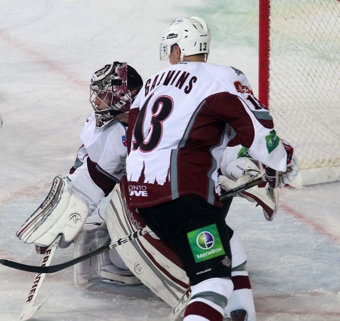 Hokejový brankář Maris Jučers hlídá s pomocí Guntise Galvinše svojí branku v utkání KHL 2012/13 mezi Lvem Praha s Dinamem Riga .