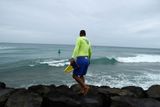 Surfař vyhlíží vlny, zatímco se bouře přibližuje hlavnímu městu Honolulu. Přináší s sebou vítr, který vane rychlostí až 190 kilometrů za hodinu.