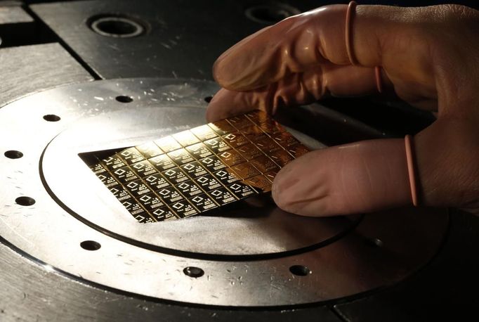 An employee takes a gold Combibar out of a press machine at a plant of gold refiner and bar manufacturer Valcambi SA in the southern Swiss town of Balerna December 20, 2012. The divisible gold combibar has a purity of 99.9 percent, weighs 50 grams and also has predetermined breaking points which allow it to be easily separated without any loss of material into 1 gram pieces. Picture taken December 20, 2012. To match story SWISS-GOLD/ REUTERS/Michael Buholzer (SWITZERLAND - Tags: BUSINESS EMPLOYMENT) Published: Pro. 21, 2012, 10:31 dop.