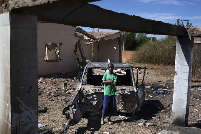 Douentza resident Hamidou Dicko stands next to a charred vehicle hit by French air strikes in the remains of a hotel in Douentza January 29, 2013. The hotel was used as a base for Islamists and was hit by French air strikes over a week ago. REUTERS/Joe Penney (MALI - Tags: CIVIL UNREST POLITICS CONFLICT) Published: Led. 29, 2013, 2 odp.