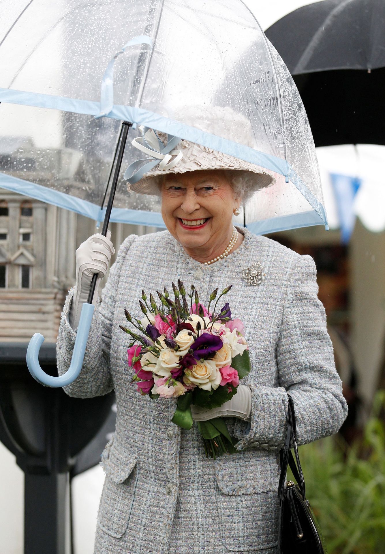 FILE PHOTO: Britain's Queen Elizabeth shelters under an umbrella as she visits the "Wild London" exhibition in Richmond