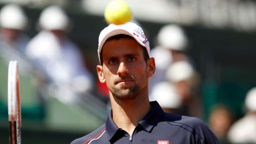 Srbský tenista Novak Djokovič sleduje míček v duelu se Slovincem Blazem Kavčičem ve 2. kole French Open 2012.