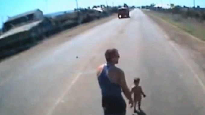 Před autem se objevilo malé děcko. Řidič ho odnese do bezpečí.