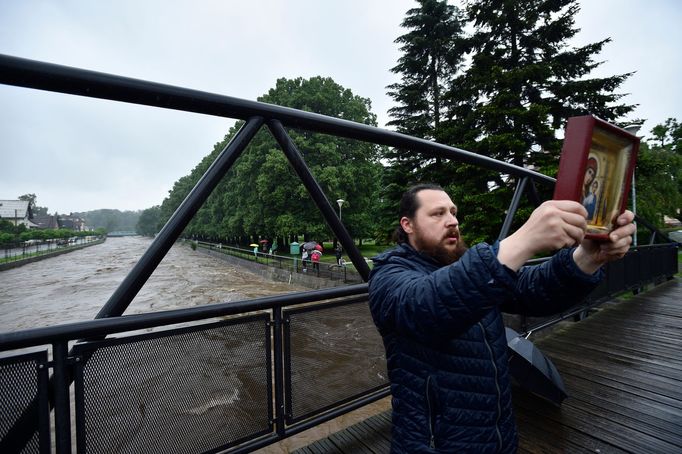 Muž s pravoslavnou ikonou na mostě přes vzedmutou Smědou ve Frýdlantu. (21. 6. 2020)