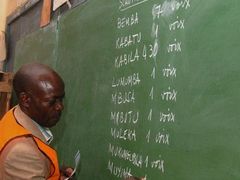 Zaměstnanec volební komise z Alfajire píše během nočního sčítání na tabuli výsledky