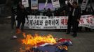 Activists from an anti-North Korea civic group burn a North Korea flag in front of banners bearing anti-North Korea messages near the U.S. embassy in central Seoul February 12, 2013. North Korea conducted its third-ever nuclear test on Tuesday, a move likely to anger its main ally China and increase international action against Pyongyang and its new young leader, Kim Jong-un. U.N. Secretary-General Ban Ki-moon condemned North Korea's test, saying it was a "clear and grave violation" of U.N. Security Council resolutions. The banner in the background reads, "Cease nuclear test and cooperate with the international powers!� REUTERS/Kim Hong-Ji (SOUTH KOREA - Tags: CIVIL UNREST POLITICS TPX IMAGES OF THE DAY) Published: Úno. 12, 2013, 8 dop.