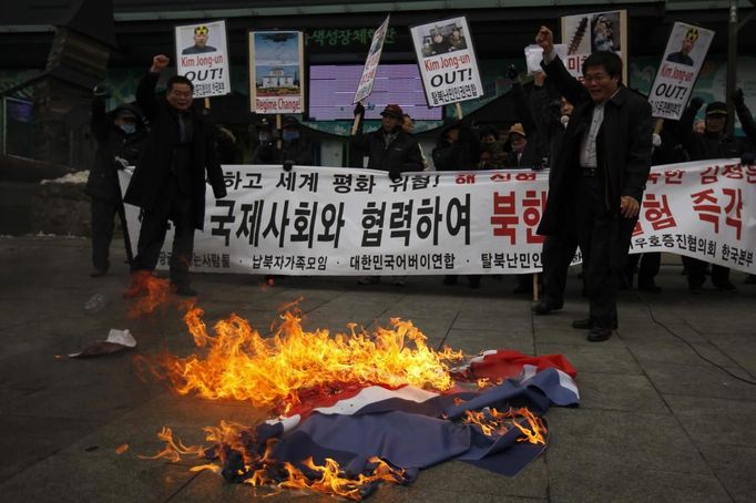 Activists from an anti-North Korea civic group burn a North Korea flag in front of banners bearing anti-North Korea messages near the U.S. embassy in central Seoul February 12, 2013. North Korea conducted its third-ever nuclear test on Tuesday, a move likely to anger its main ally China and increase international action against Pyongyang and its new young leader, Kim Jong-un. U.N. Secretary-General Ban Ki-moon condemned North Korea's test, saying it was a "clear and grave violation" of U.N. Security Council resolutions. The banner in the background reads, "Cease nuclear test and cooperate with the international powers!� REUTERS/Kim Hong-Ji (SOUTH KOREA - Tags: CIVIL UNREST POLITICS TPX IMAGES OF THE DAY) Published: Úno. 12, 2013, 8 dop.