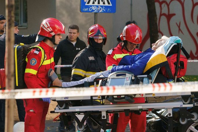 Hasiči a záchranáři odnášejí osobu na nosítkách z místa výbuchu v bytovém domě v Bukurešti, Rumunsko, 17. října 2025.