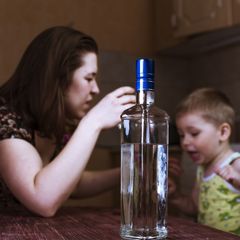Matka s dítětem a lahví alkoholu