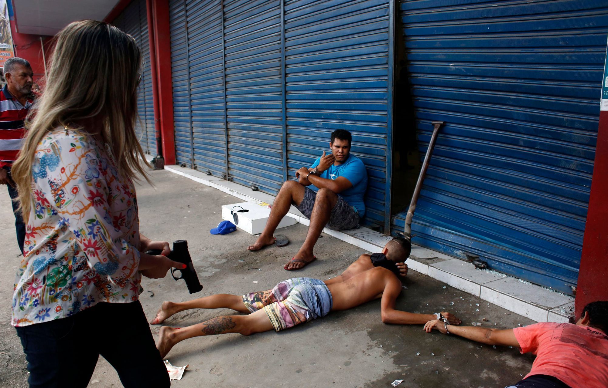 Civil police officer detain young suspects after a store was looted during a police strike in Recife
