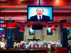 Obsluha pizzerie Simferopolu sleduje projev ruského prezidenta Vladimira Putina.
