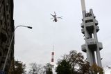 Vrtulník klesá s druhým ze tří vyměňovaných dílů podél veže vysílače. Původní anténní nástavec měřil přibližně 23 metrů a vážil zhruba devět tun.