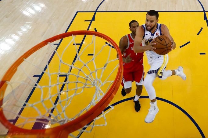 Stephen Curry z Golden State míří s míčem do koše v šestém zápase semifinále NBA 2018 proti Houstonu. Vzadu přihlíží Trevor Ariza.